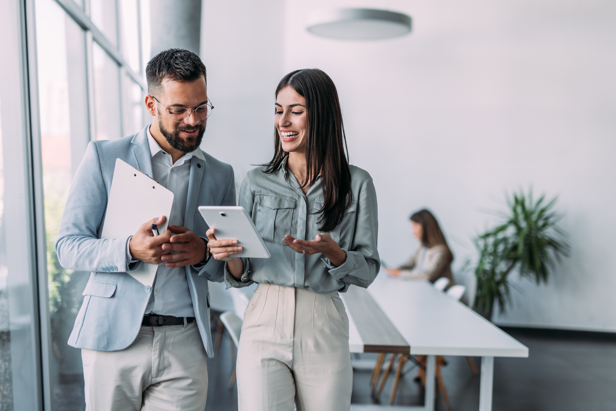 Shot of a two confident business persons talking in the work place. Two colleagues using a digital tablet while walking in a modern office. 